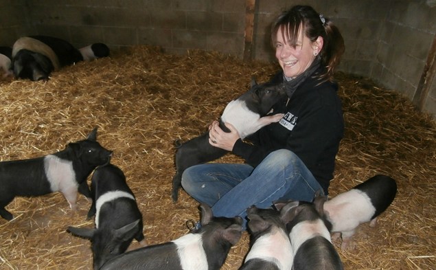 Louise sat on straw surrounded by piglets