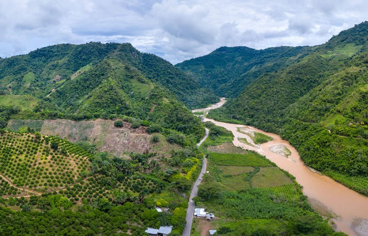 Lush green mountainous landscape. Muddy river flowing through a valley
