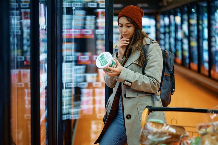 Woman checking label on food packaging in a super market